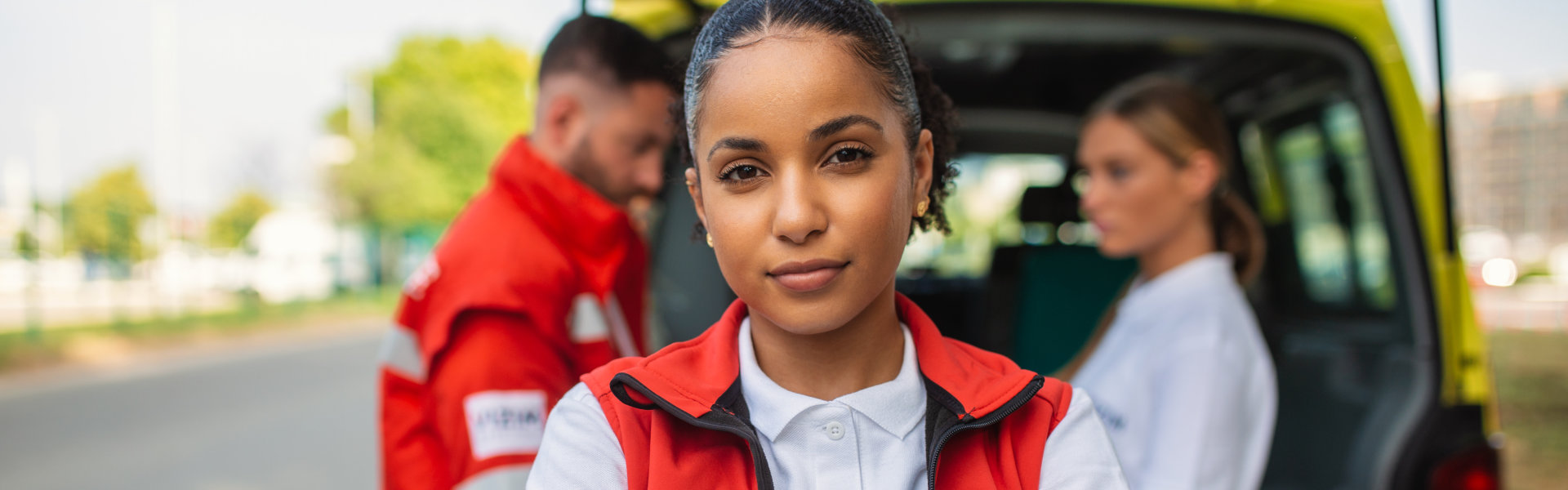 young paramedic looking at the camera with her team in the background
